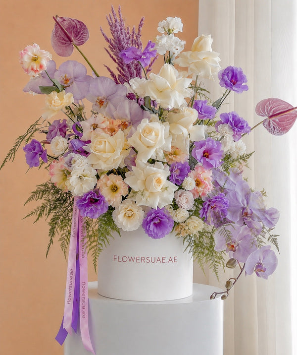 Colorful flower arrangement in a white box with 'FLOWERSUAE.AE' branding on a light background.