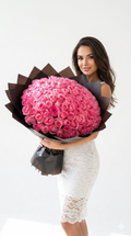 Woman holding a large bouquet of pink flowers against a white background